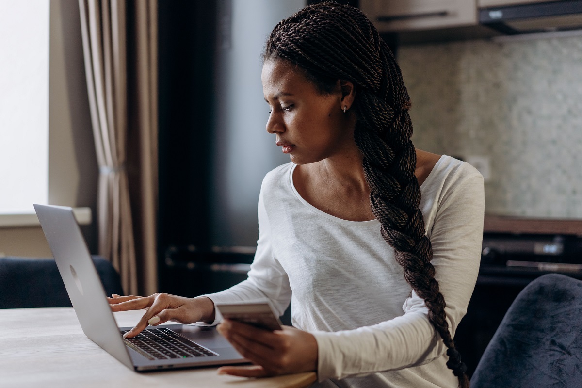 A woman uses a laptop while holding a payment card - THEWILL NEWS MEDIA Loan