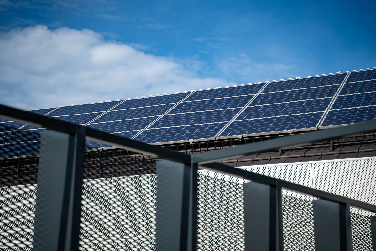 Solar - THEWILL NEWS MEDIA Solar panels on a rooftop with a metal railing in the foreground and a clear blue sky above.
