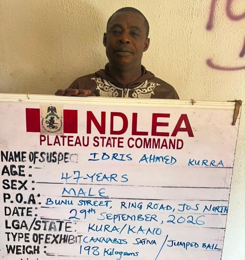 Idris - THEWILL NEWS MEDIA A man stands behind a display board reading'NDLEA Plateau State Command'; handwritten suspect details are visible on the board.