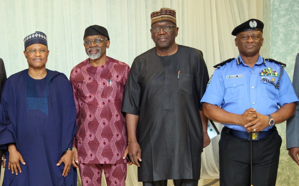 Meeting on State police - THEWILL NEWS MEDIA Four men stand side by side indoors, wearing traditional Nigerian attire and a police uniform for a formal group photo.