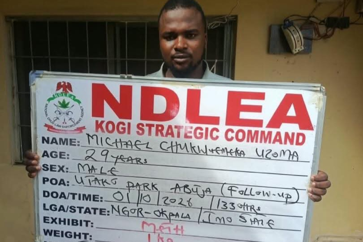 Michael Uzoma - THEWILL NEWS MEDIA Man holding a large NDLEA Kogi Command identification board with handwritten details