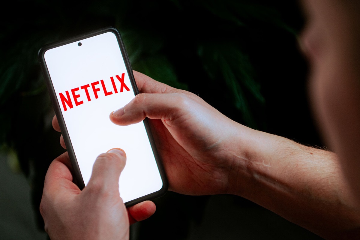 NETFLIX - THEWILL NEWS MEDIA A person holds a smartphone displaying the Netflix logo on a white screen.