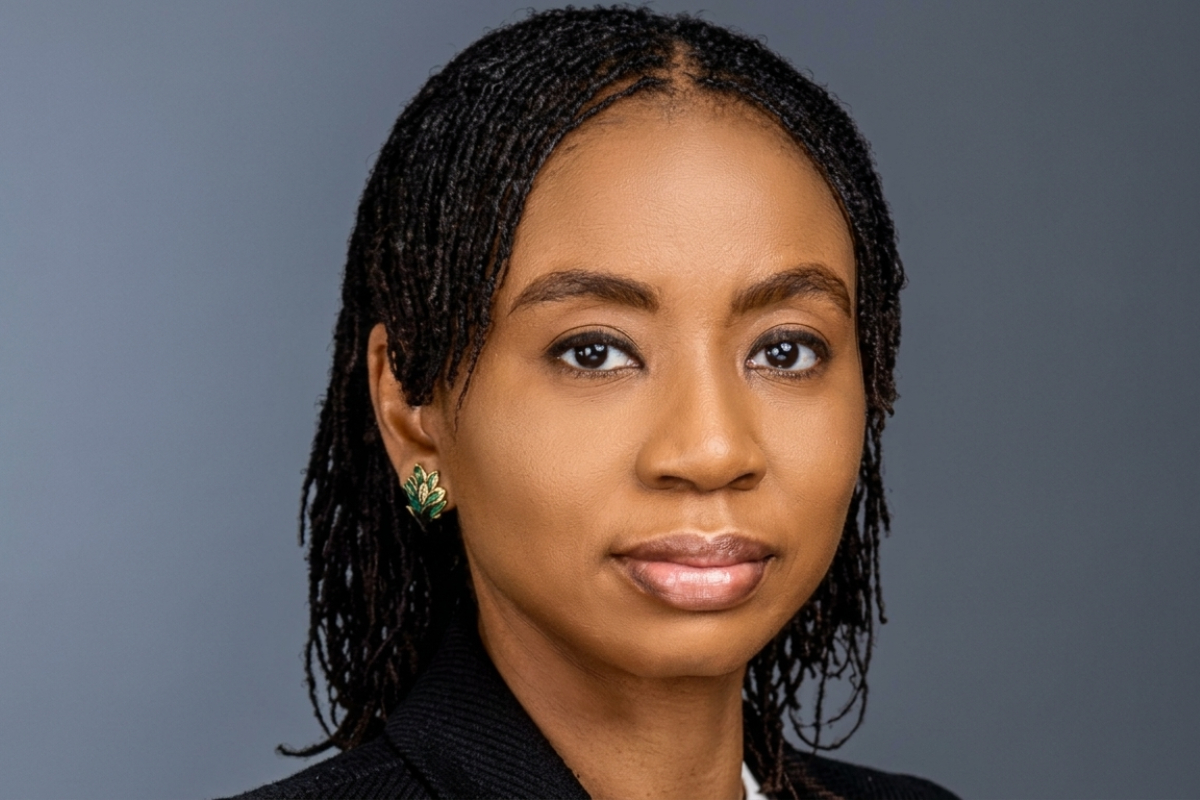 Omolola Oloworaran - THEWILL NEWS MEDIA Close-up portrait of a woman with braided hair, wearing green leaf-shaped earrings, looking at the camera against a gray background.