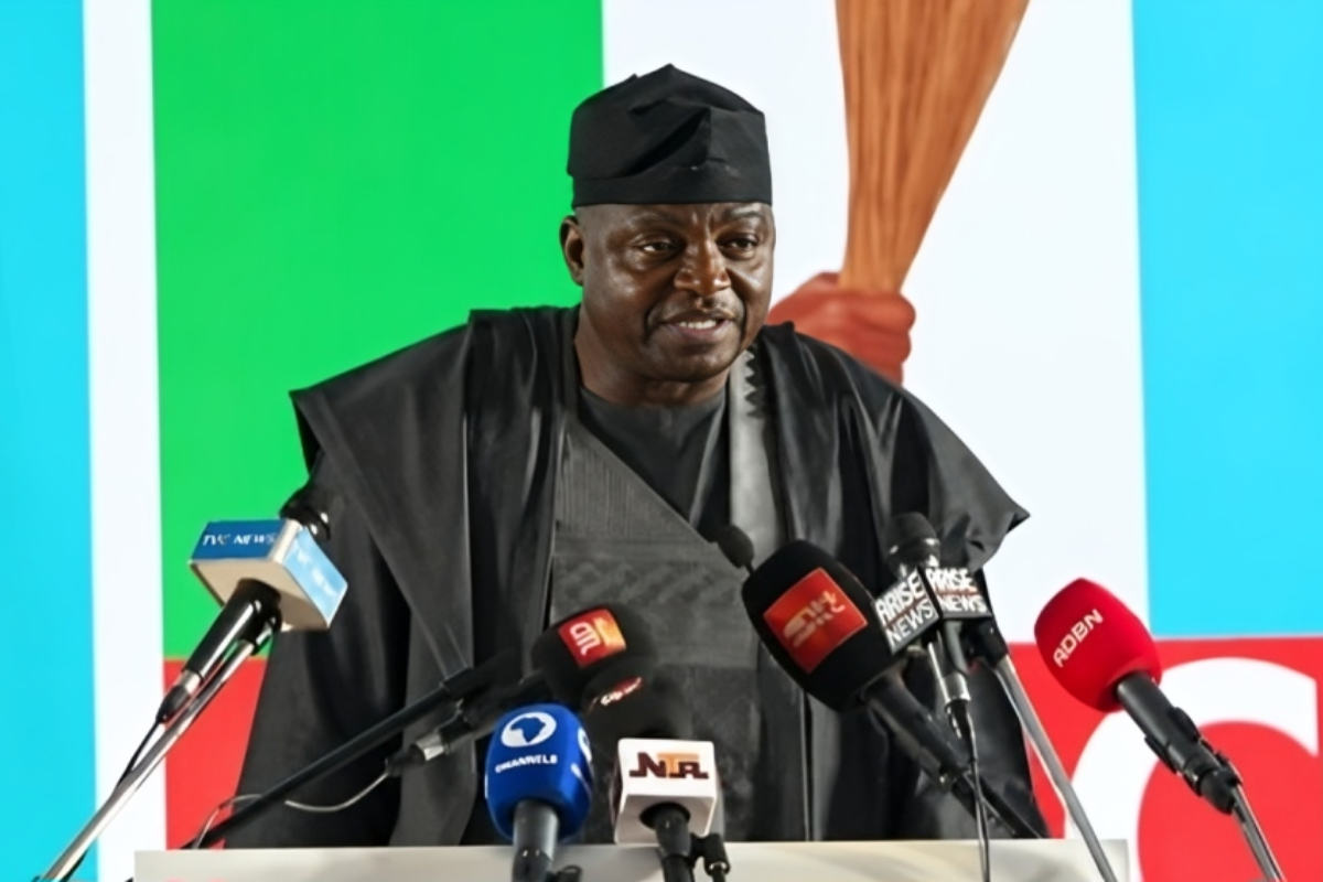 Prof Nentawe Yilwatda - THEWILL NEWS MEDIA Man in traditional black attire delivers a speech at a press conference, multiple microphones in front of him at a podium.