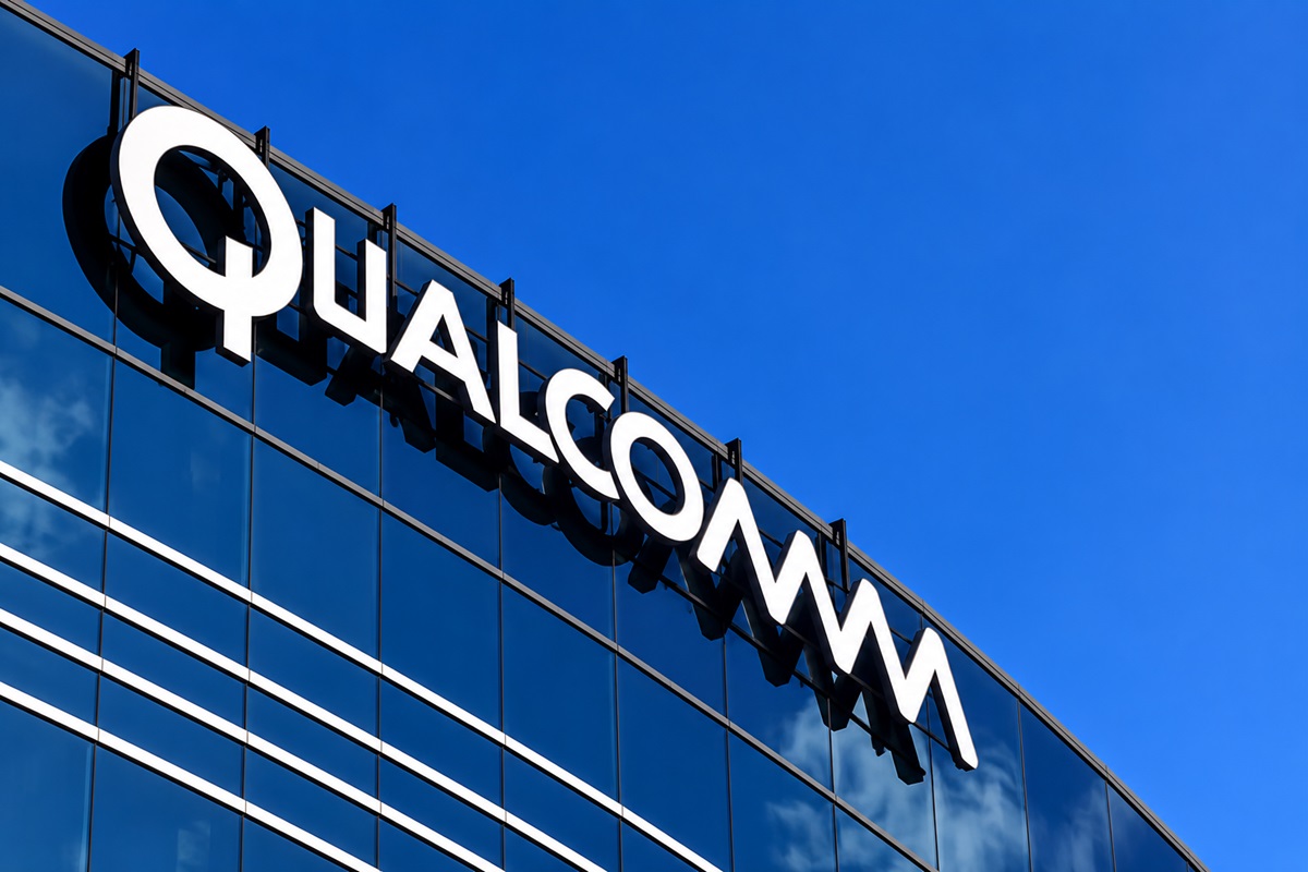 Qualcomm - THEWILL NEWS MEDIA Qualcomm logo on a glass office building with a clear blue sky behind it
