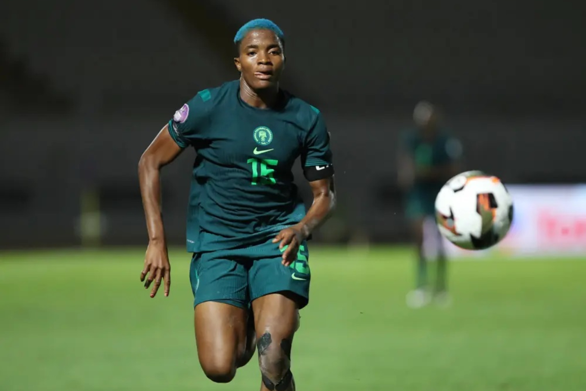 Rasheedat Ajibade - THEWILL NEWS MEDIA Soccer player in a teal kit (number 15) runs toward a ball on a grass field at night.