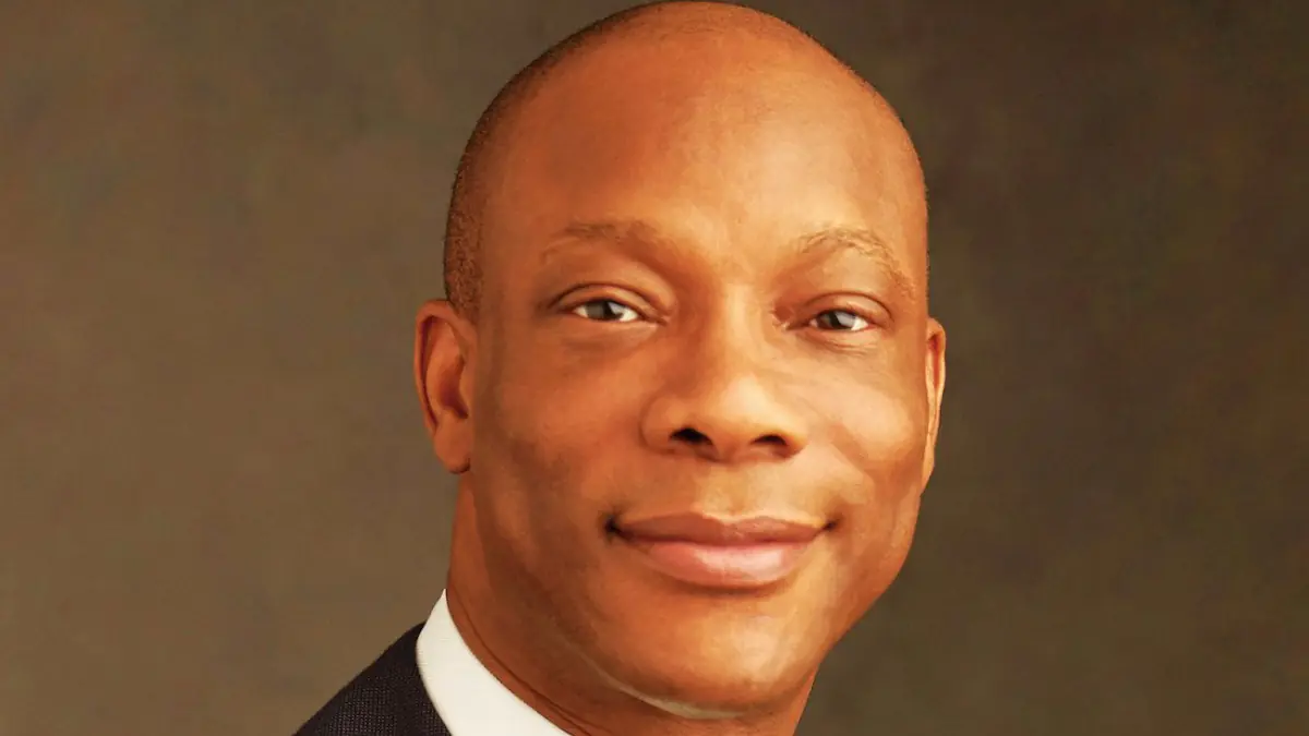 Segun Agbaje - THEWILL NEWS MEDIA Head-and-shoulders portrait of a smiling man in a dark suit against a brown backdrop.