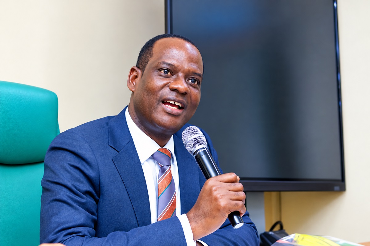 Taiwo Oyedele - THEWILL NEWS MEDIA Man in a blue suit and striped tie speaks into a handheld microphone in a conference room.