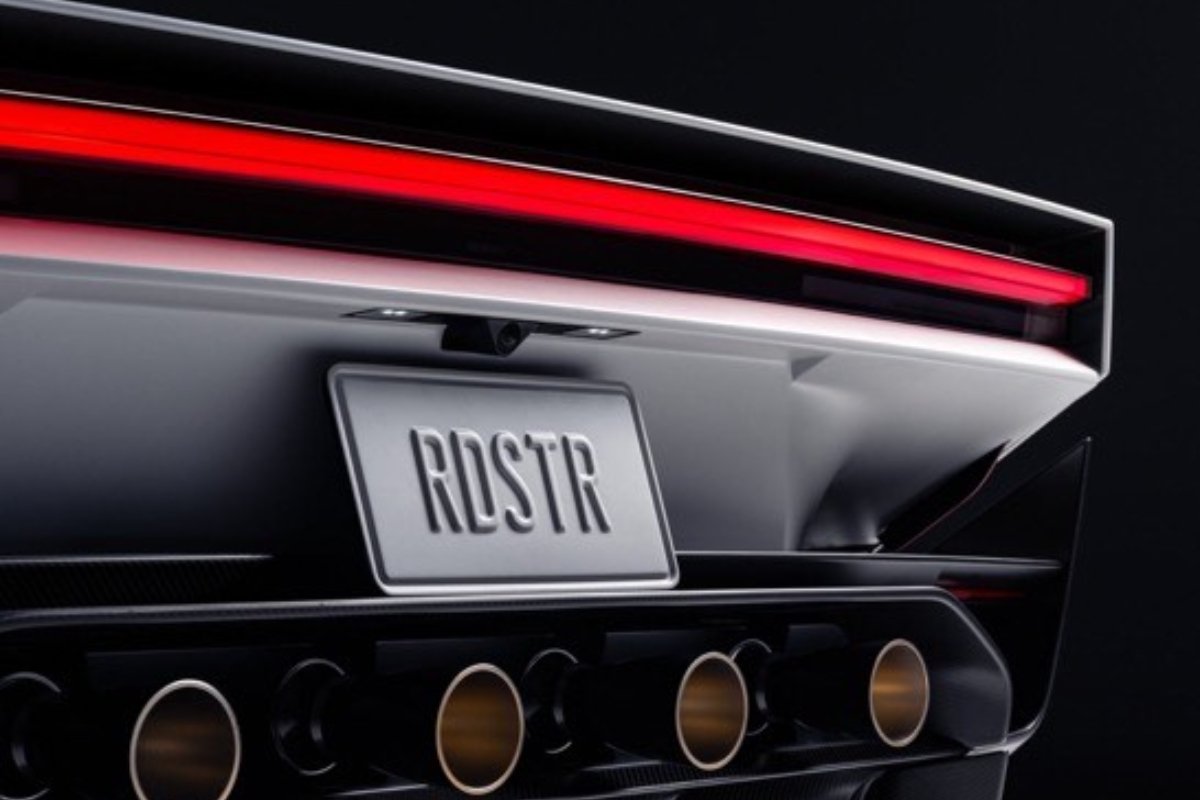 Tesla Roadster - THEWILL NEWS MEDIA Close-up of a sleek sports car rear showing a red horizontal tail light, quad exhaust tips, and a tilted license plate reading RDSTR/RDSTR.