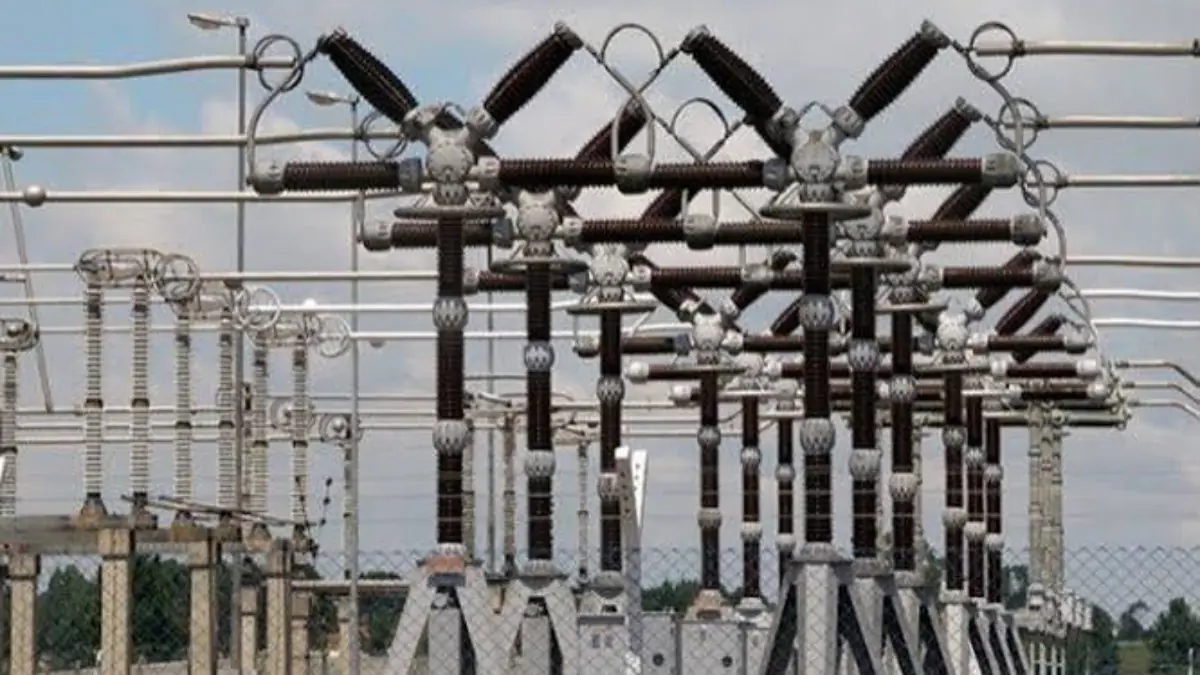 Transmitters - THEWILL NEWS MEDIA High-voltage electrical substation with a dense network of insulators and bus bars, a chain-link fence visible in the foreground under a cloudy sky.