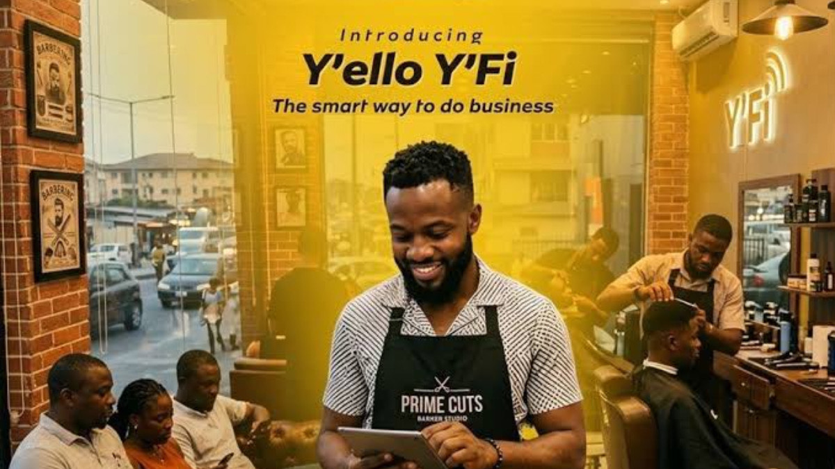 Yello YFi - THEWILL NEWS MEDIA Barber shop scene with a smiling barber using a tablet; yellow promo banner reads 'Introducing Y'ello YFi — The smart way to do business'.